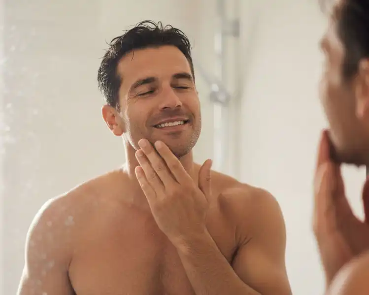 Hombre cuidando su piel frente al espejo, destacando el uso del colágeno en rutinas masculinas